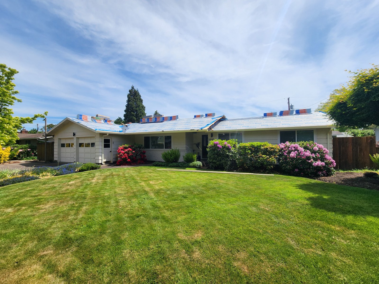 The ranch home dried in with synthetic underlayment and new shingle bundles staged on the roof.